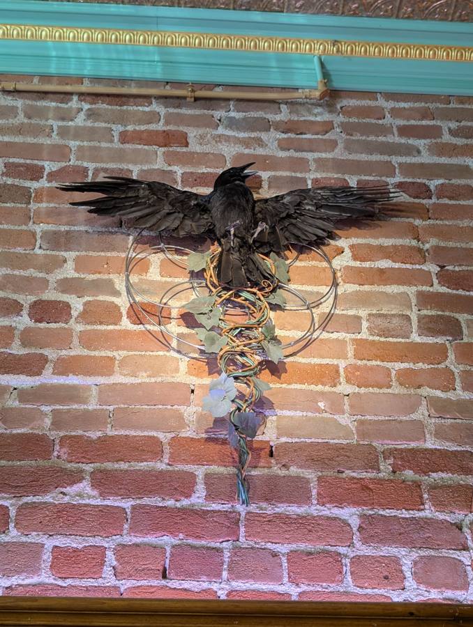 Raven sculpture mounted on a brick wall